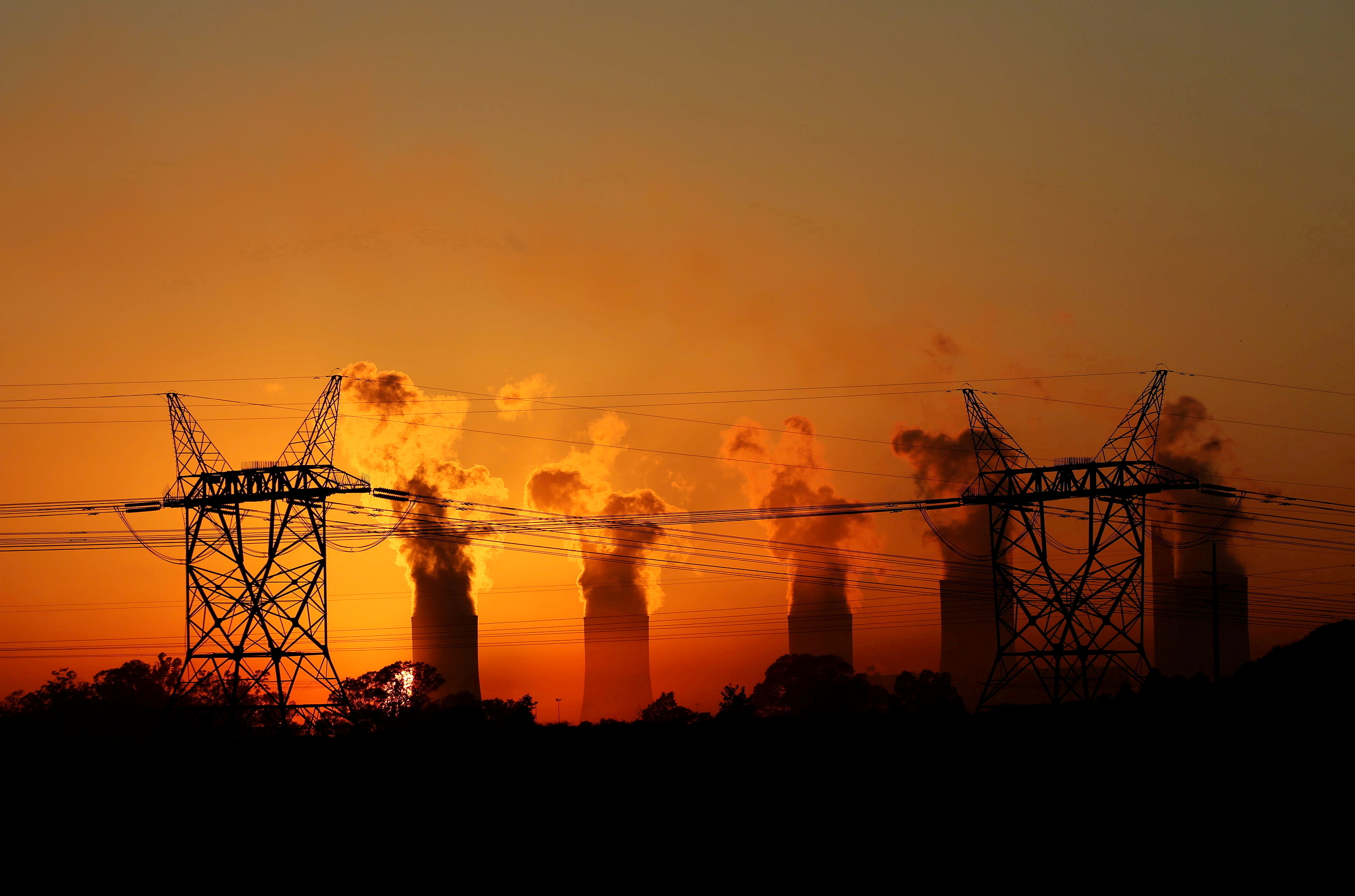 Electricity pylons are seen in front of the cooling towers at the Lethabo Thermal Power Station, an Eskom coal-burning pow...