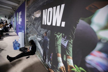 A delegate sits on the floor and works at the UN Climate Change Conference (COP26) in Glasgow, Scotland, Britain, November 11, 2021. Photo by Yves Herman/REUTERS