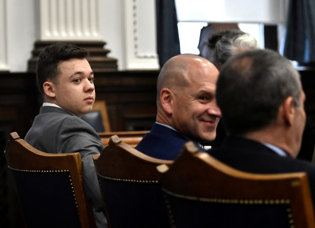 Kyle Rittenhouse looks back as he sits with his attorneys before the day starts at the Kenosha County Courthouse in Kenosh...