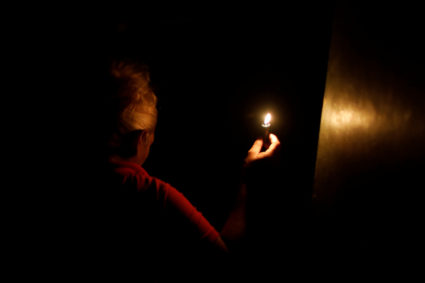 Woman uses a candle as she enters her house during the second day of a blackout in Caracas,