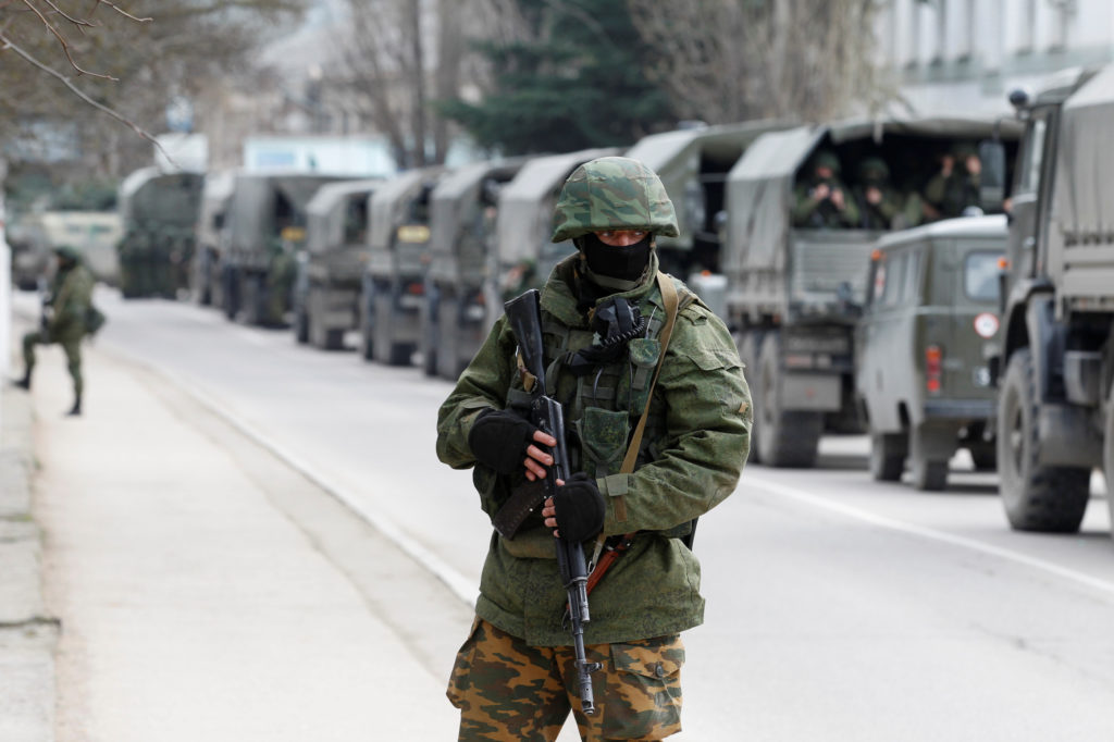 FILE PHOTO: Armed servicemen wait in Russian army vehicles outside a Ukranian border guard post in the Crimean town of Bal...