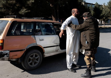 Taliban fighter searches a man at a checkpoint in Kabul