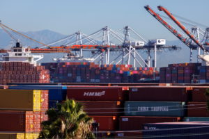 Stacked containers are shown as ships unload their cargo at the Port of Los Angeles