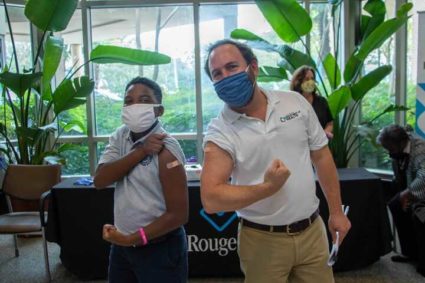 Louisiana State Health director flexes his arm with a child after getting a shot.