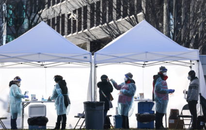 Health workers administer COVID-19 tests at a free public testing site in Washington