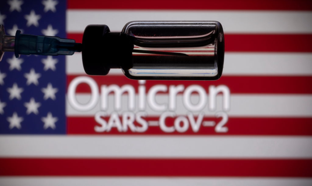 FILE PHOTO: A vial and a syringe are seen in front of a displayed United States' flag and words "Omicron SARS-CoV-2" in th...