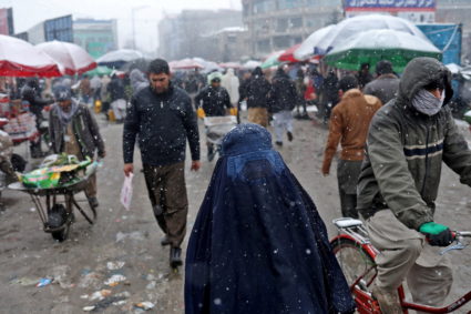 FILE PHOTO: An Afghan woman walks on the street during a snowfall in Kabul