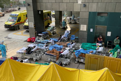Patients wearing face masks lie in bed at a makeshift treatment area outside a hospital, following the coronavirus disease...