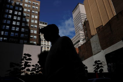 A man is seen silhouetted wearing a protective face mask, amid the coronavirus disease (COVID-19) pandemic, walking near t...