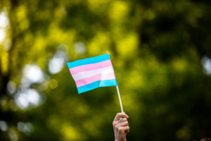 Transgender rights activist waves a transgender flag as they protest the killings of transgender women this year, at a ral...