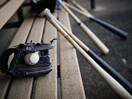 Baseball glove with ball and bats in dugout
