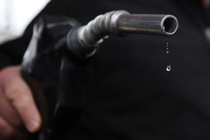 Gasoline drips out of a nozzle held by a gas station mechanic in Somerville