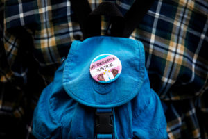 A "We Deserve Justice" button is seen as people protest the recent killings of three trans women, Muhlaysia Booker, Claire...
