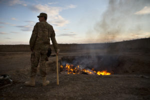 A U.S. Army soldier watches bottled water that had gone bad burn in a burn-pit at Forward Operating Base Azzizulah in Maiwand District, Kandahar Province, Afghanistan, February 4, 2013. Photo by Andrew Burton/REUTERS