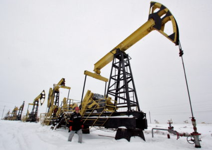 FILE PHOTO: A worker walks past pump jacks at UdmurtNeft's Gremikhinskoye oil field east of Izhevsk