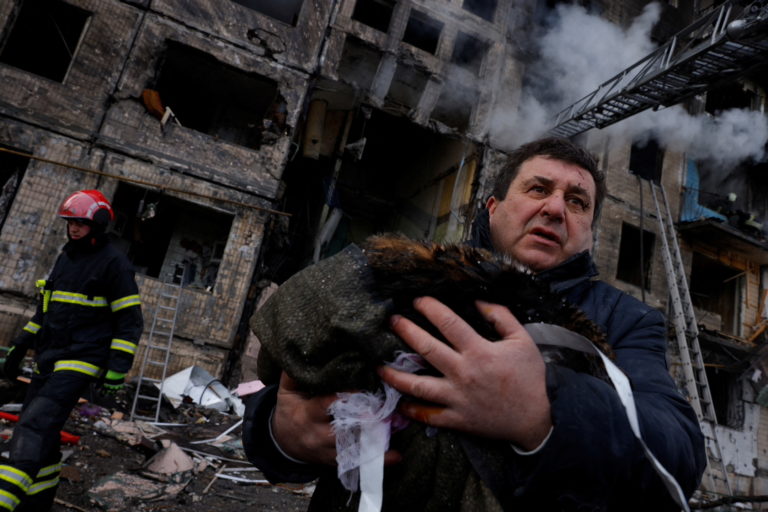 A resident carries his cat that was rescued from his home after it was hit by a shell in the Obolon district in Kyiv