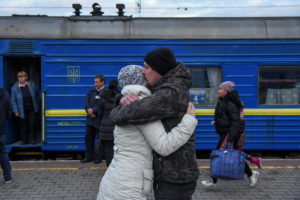 A couple embraces as passengers, including people fleeing Russia's invasion of Ukraine, board a train to leave the city of...