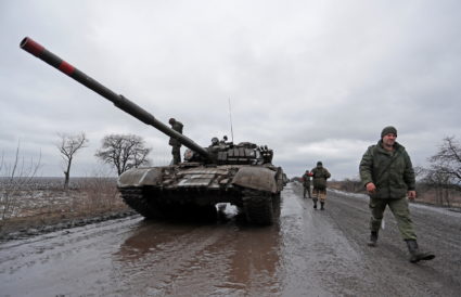 Servicemen of pro-Russian militia walk next to a military convoy in the Luhansk region