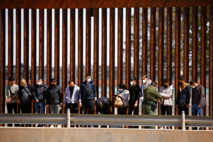 Asylum-seeking migrants are detained by a U.S. Border Patrol agent after crossing the Rio Bravo river to turn themselves in to request asylum in El Paso, Texas, U.S., as seen from Ciudad Juarez, Mexico March 30, 2022. Photo by Jose Luis Gonzalez/REUTERS