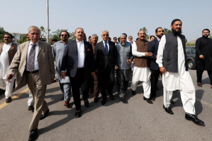 Pakistani lawmakers of the united opposition walk towards the parliament house building to cast their vote on a motion of ...