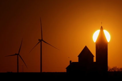 Power-generating windmill turbines and the church of Noreuil village are pictured during sunset at a wind park near Cambrai, France, March 18, 2022. Photo by Pascal Rossignol/REUTERS