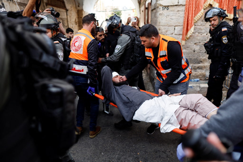 Rescue personnel evacuate an injured man outside the compound that houses Al-Aqsa Mosque, known to Muslims as Noble Sanctu...