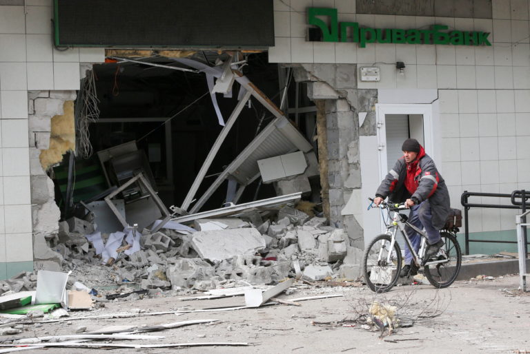 A man rides a bicycle near a damaged branch of PrivatBank in Mariupol