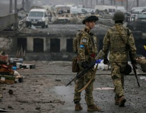 Ukrainian servicemen stand by a destroyed bridge as Russia's invasion of Ukraine continues, in the town of Irpin outside Kyiv