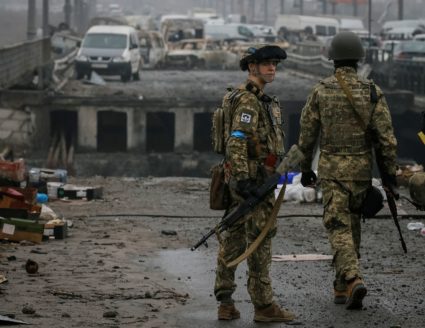 Ukrainian servicemen stand by a destroyed bridge as Russia's invasion of Ukraine continues, in the town of Irpin outside Kyiv