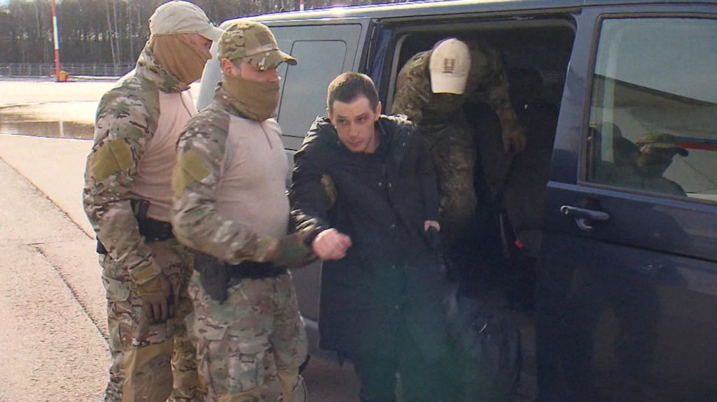 Former U.S. Marine Trevor Reed is escorted to a plane as part of a prisoner swap, in Moscow