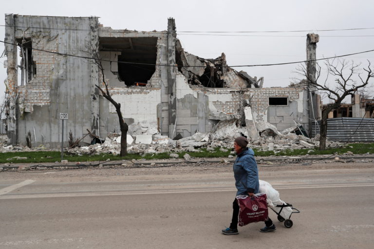 FILE PHOTO: A local resident walks past a destroyed building in Mariupol