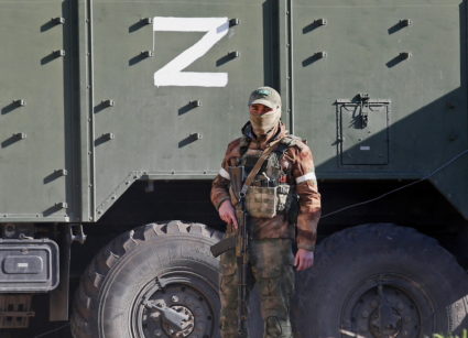 A service member of pro-Russian troops stands next to a military vehicle in Mariupol