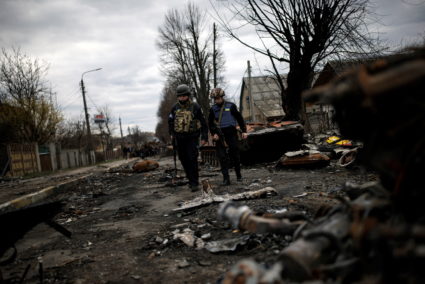 Volunteers of the Territorial Defence Forces walk next to destroyed Russian tanks and armoured vehicles in Bucha
