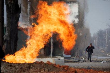 A man walks past a burning gas pipeline that was hit during shelling from Russian positions in a neighbourhood in northern...