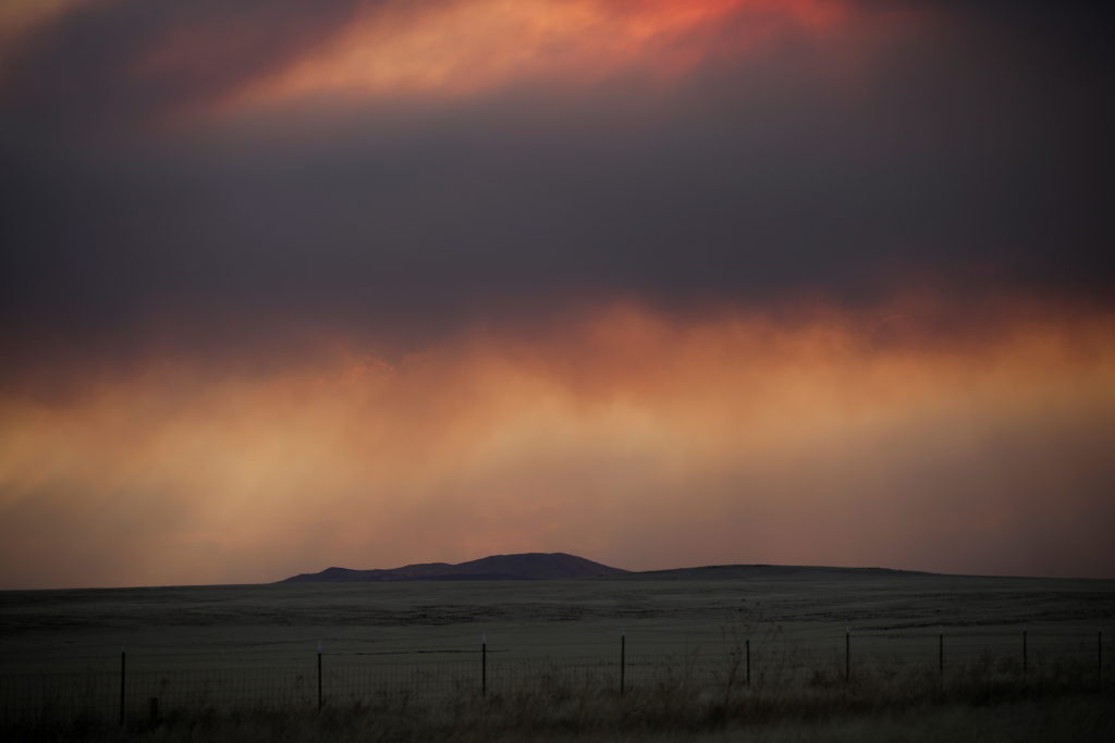 A general view of the landscape with plumes of smoke from the Hermits Peak and Calf Canyon fires filling the sky, near Oca...