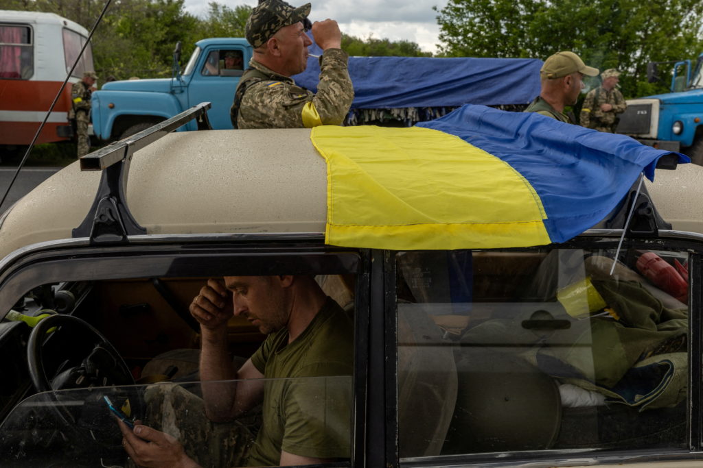 Ukrainian soldiers and volunteers from territorial defense forces pause on the road, near Oleksandriya