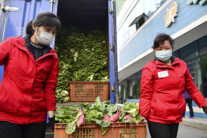 Workers wearing protective face masks carry vegetables, amid growing fears over the spread of COVID-19, in Pyongyang