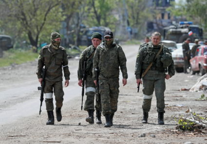 Service members of pro-Russian troops walk along a street in Mariupol
