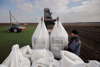 FILE PHOTO: A local farm worker unloads Ukrainian-made fertiliser from a truck to use on a wheat field near the village of...