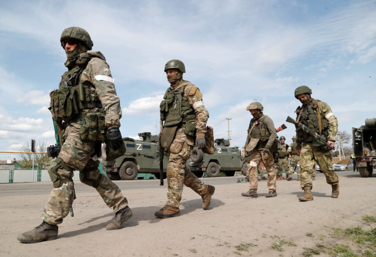 Service members of pro-Russian troops walk near a temporary accommodation centre for evacuees in Bezimenne