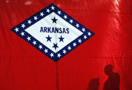 Campaign workers cast shadows on the Arkansas state flag while preparing for a news conference for Democratic presidential...