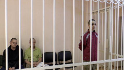 A still image shows Britons Aiden Aslin, Shaun Pinner and Moroccan Brahim Saadoun in a courtroom cage at a location given ...