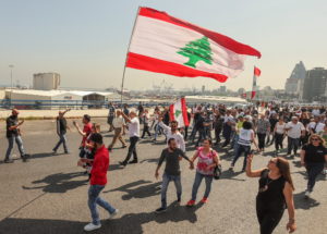 People hold Lebanese flags as newly-elected Lebanese independent lawmakers walk towards parliament for the first session p...