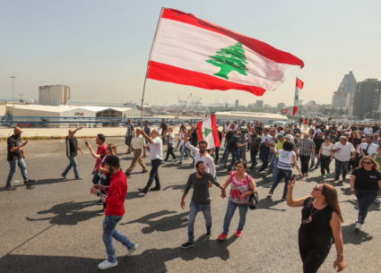 People hold Lebanese flags as newly-elected Lebanese independent lawmakers walk towards parliament for the first session p...