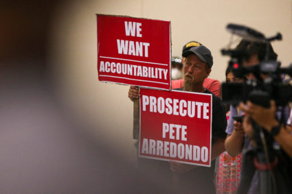 Michael Brown, an Uvalde community member who has a child that was enrolled ar Robb Elementary, holds signs calling for police accountability during a hearing by a Texas House Investigative Committee at the SSGT Willie de Leon Civic Center in Uvlade, Texas, U.S. July 17, 2022. Photo by Aaron E. Martinez/USA Today Network via REUTERS