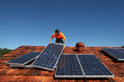 Solar system installer Thomas Bywater adjusts new solar panels on the roof of a house in Sydney August 19, 2009. Photo by Tim Wimborne/REUTERS