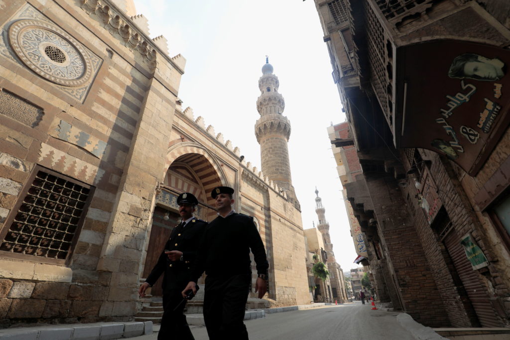 Egyptian police officers walk by Jama'a Al-Aqsunqur in Cairo