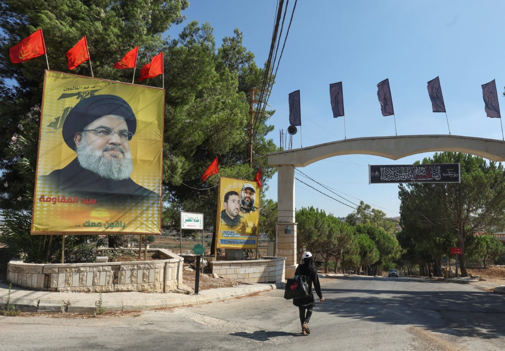 A woman walks past a poster depicting Lebanon's Hezbollah leader Sayyed Hassan Nasrallah in the town of Yaroun