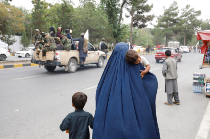 An Afghan woman walks with her children on the anniversary of the fall of Kabul on a street in Kabul, Afghanistan, August 15, 2022. Photo by Ali Khara/REUTERS