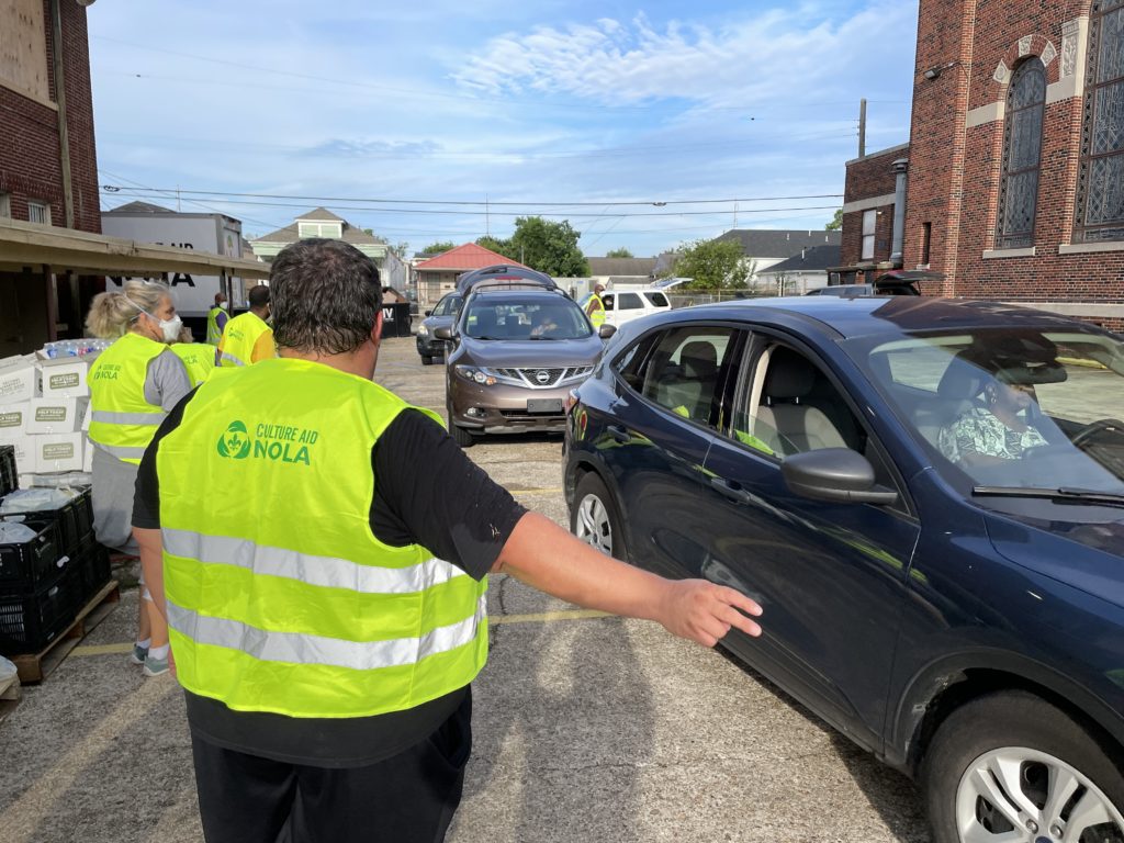Volunteer directs cars at a food giveaway.